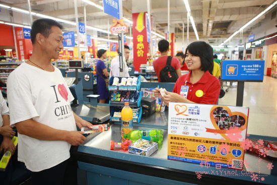 沃尔玛购物广场北京宣武门店收银员正在向顾客介绍你“沃”一起，为爱加餐项目的捐款信息